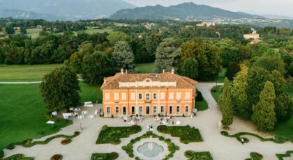A stunning aerial view of a historic villa and gardens in Italy, surrounded by lush greenery.