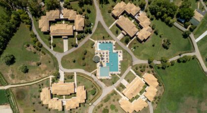 Aerial image showcasing resort villas and swimming pool in lush surroundings, Corfu, Greece.