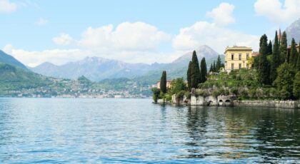 Picturesque view of Varenna, Italy with villa by Lake Como and mountain backdrop.