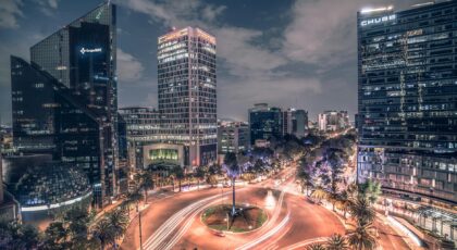 Stunning nighttime long exposure of Mexico City's bustling traffic circle with illuminated skyscrapers.
