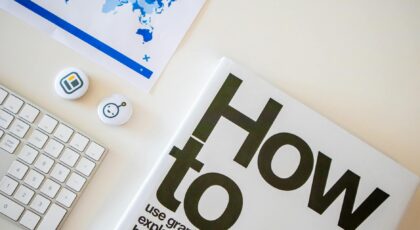 Stylish desk setup with a how-to book, keyboard, and world map on paper.