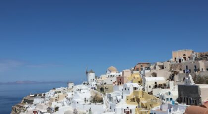 Explore the iconic whitewashed architecture of Oia, Santorini under a clear blue sky.