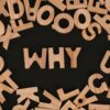Scattered wooden alphabet letters with the word WHY at the center on a black background in a flat lay arrangement.