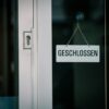 A close-up view of a 'Geschlossen' sign hanging on a door, indicating closure.