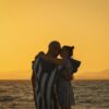 Couple embracing at Naxos beach during a golden sunset, exuding romance.