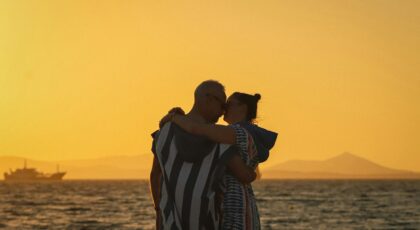 Couple embracing at Naxos beach during a golden sunset, exuding romance.