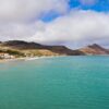 Breathtaking view of Porto Santo's coastline with turquoise waters and mountainous backdrop, Madeira, Portugal.