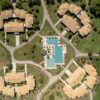 Aerial image showcasing resort villas and swimming pool in lush surroundings, Corfu, Greece.