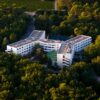 Aerial shot of a modern hotel nestled in a lush green forest.