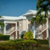 Exterior view of a tropical resort with classic architecture and lush palm trees under a clear blue sky.