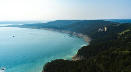 Discover the breathtaking aerial view of a tranquil lake surrounded by lush hills in Texas, showcasing nature's beauty.