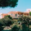 Charming Mediterranean villa nestled in vibrant, lush gardens under a clear blue sky.