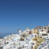 Explore the iconic whitewashed architecture of Oia, Santorini under a clear blue sky.