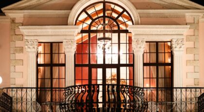 An illuminated neoclassical balcony at night showcasing ornate architecture and warm lighting.