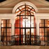 An illuminated neoclassical balcony at night showcasing ornate architecture and warm lighting.