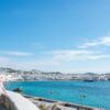 A beautiful day in Mykonos, Greece, showcasing the harbor and iconic white buildings.