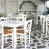 Traditional Greek cafe with white chairs and stone flooring in Naxos, Greece, ideal for tourism and travel imagery.