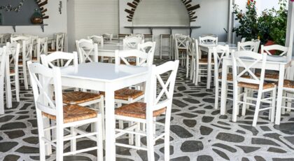 Traditional Greek cafe with white chairs and stone flooring in Naxos, Greece, ideal for tourism and travel imagery.