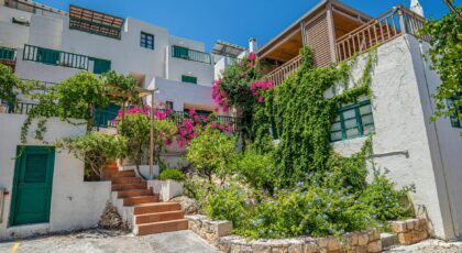 Mediterranean villa adorned with lush greenery and vibrant flowers, under a clear blue sky.