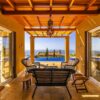 Relaxing patio at a luxury villa with sea view, featuring rattan furniture and infinity pool.