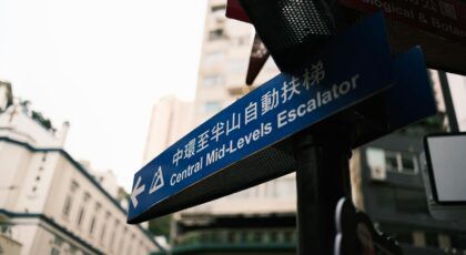 Urban street sign pointing to Central Mid-Levels Escalator in Hong Kong.