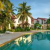 Explore a luxurious tropical resort featuring palm trees and an inviting poolside setting, perfect for leisure and relaxation.