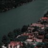 Aerial view of elegant homes along a tranquil river surrounded by lush greenery, showcasing affluence and scenic beauty.
