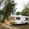 Vintage camper trailers set amidst trees in a peaceful Texas forest scene.